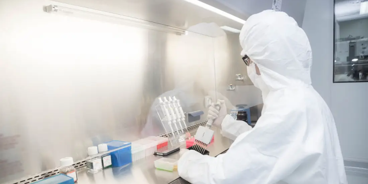 Technicien en combinaison stérile assurant l’hygiène et la sécurité au laboratoire lors de manipulations