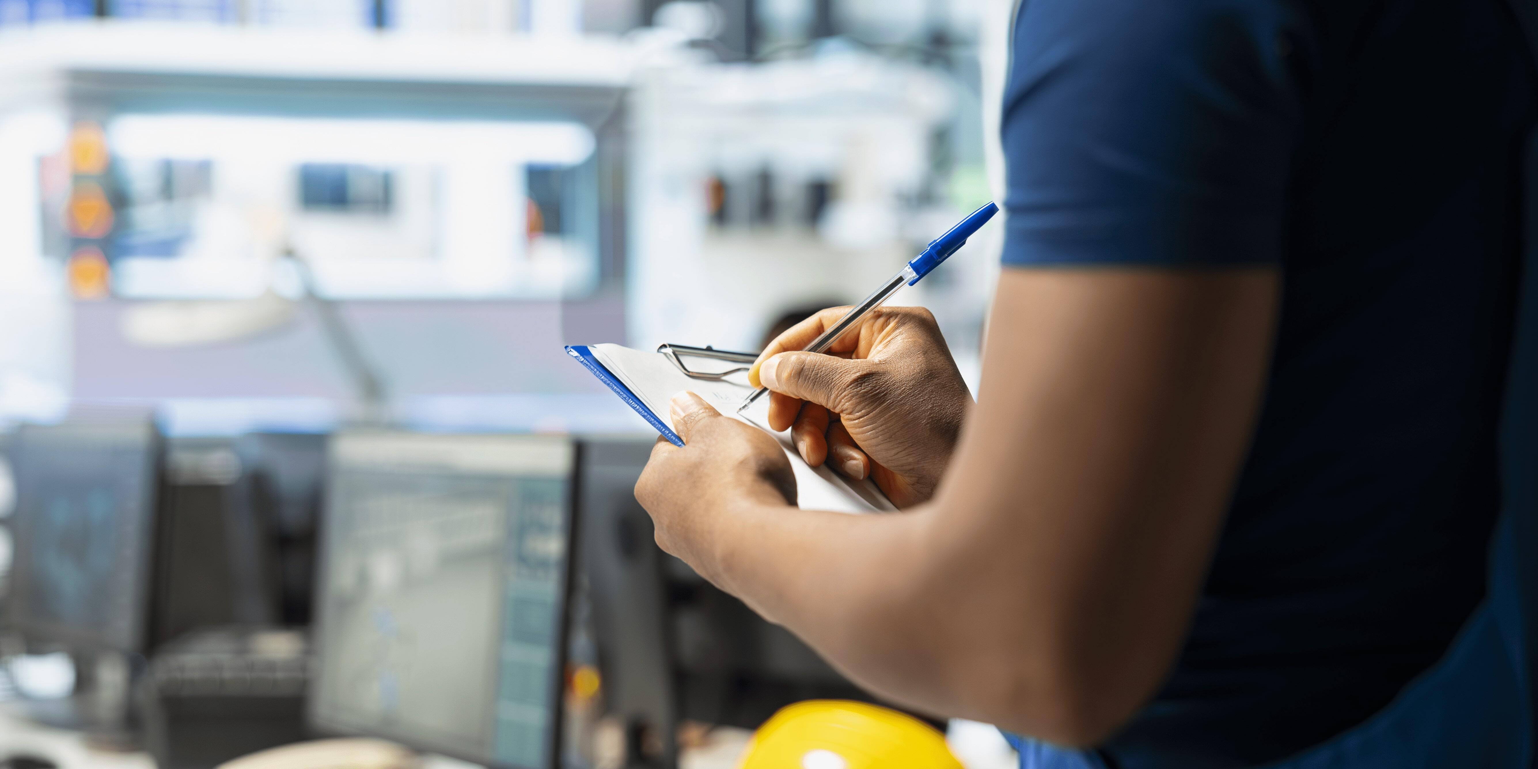 Technicien remplissant une fiche d’intervention sur site dans le cadre de la gestion des interventions de maintenance.